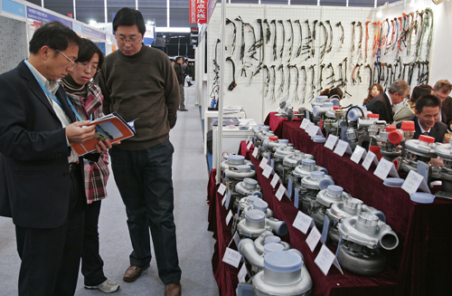 Visitors browse pamphlets at a booth displaying auto parts.