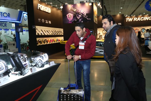 An exhibitor demonstrates a product to foreign buyers.